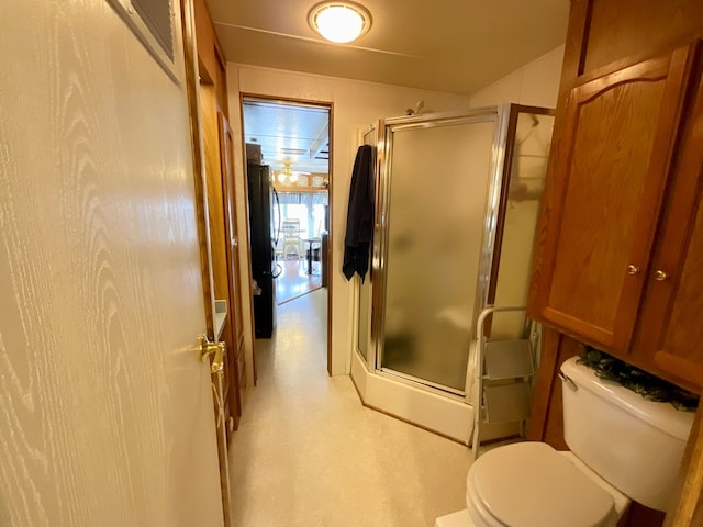 bathroom featuring toilet and a shower with shower door