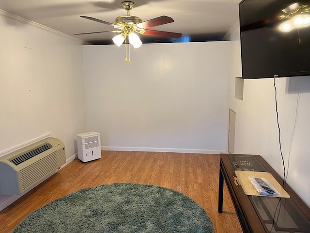 living room featuring ceiling fan, ornamental molding, a wall unit AC, and hardwood / wood-style floors