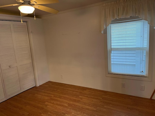 unfurnished bedroom with a closet, ornamental molding, wood-type flooring, and ceiling fan