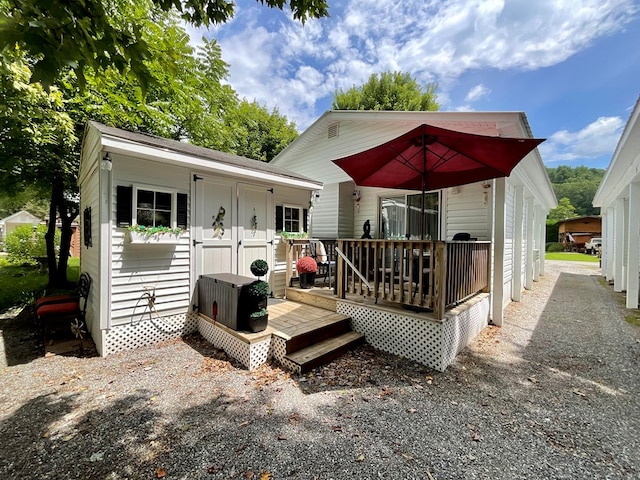 back of property featuring an outdoor structure and a deck