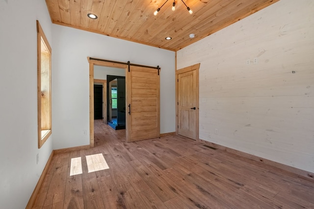 unfurnished room with a barn door, light hardwood / wood-style flooring, and wooden ceiling