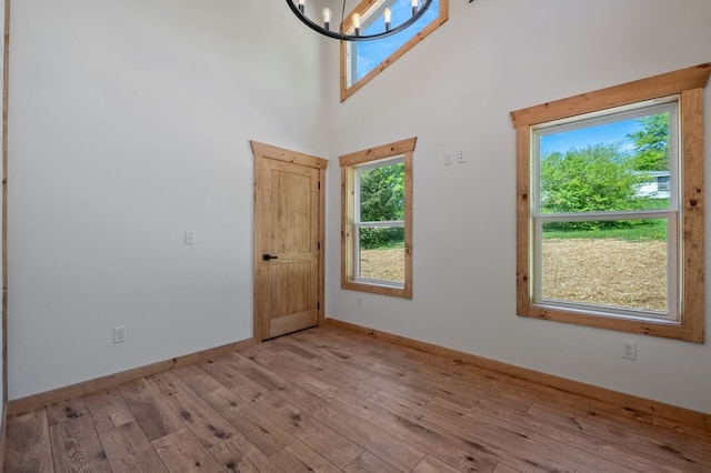 interior space with light wood-type flooring, a high ceiling, and a chandelier