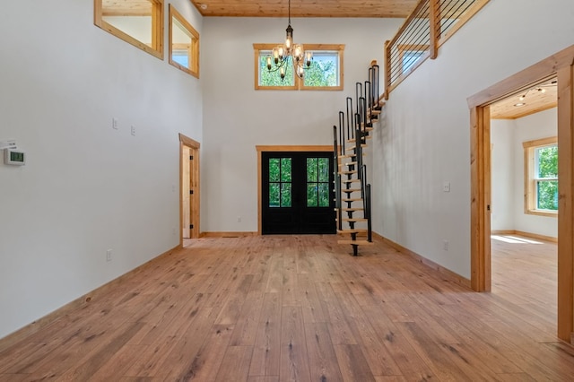 foyer entrance featuring light wood-type flooring, a towering ceiling, and a chandelier