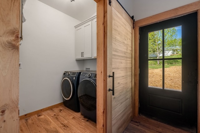 washroom featuring a barn door, separate washer and dryer, cabinets, and light wood-type flooring