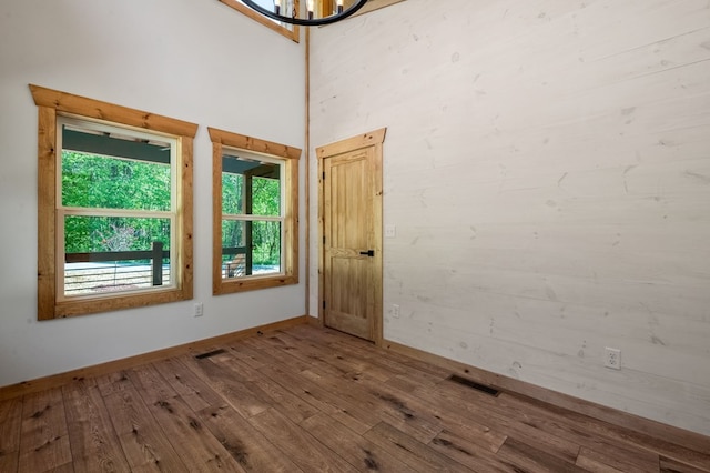 empty room with hardwood / wood-style floors and a towering ceiling