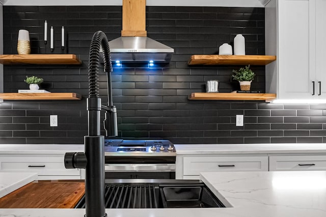 kitchen with white cabinets, decorative backsplash, light stone counters, and extractor fan