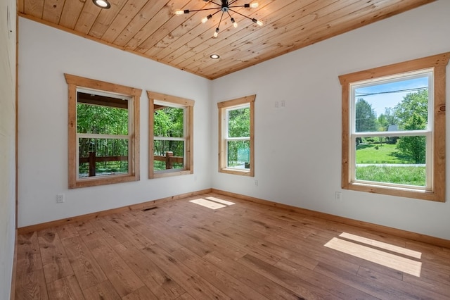 unfurnished room with light wood-type flooring, an inviting chandelier, and wood ceiling