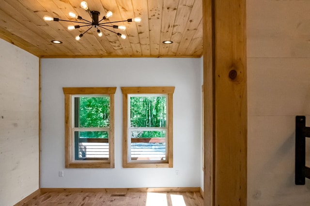 spare room featuring light hardwood / wood-style flooring, wood ceiling, vaulted ceiling, and an inviting chandelier