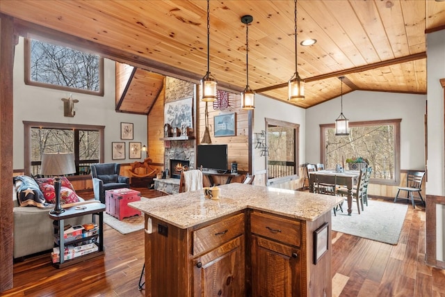 kitchen featuring dark wood finished floors, a stone fireplace, wooden ceiling, and pendant lighting