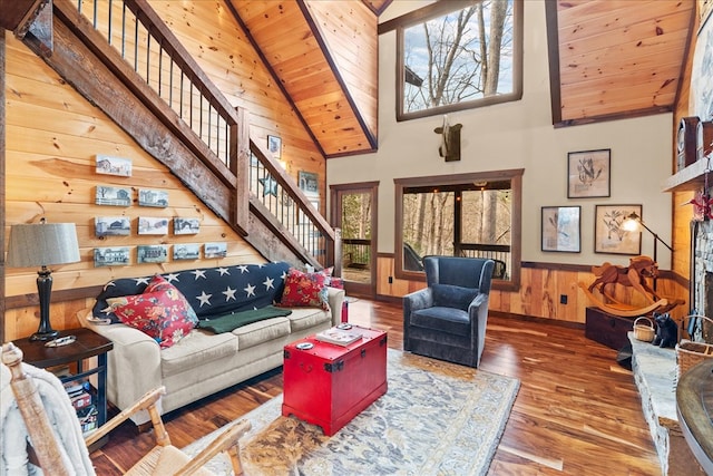 living room with stairs, plenty of natural light, a fireplace with raised hearth, and wainscoting