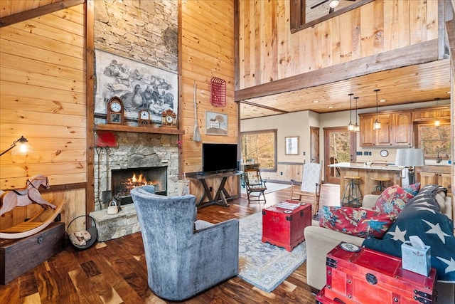 living area featuring wooden walls, a fireplace, a towering ceiling, and wood finished floors