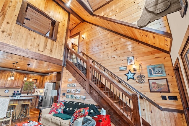 living area featuring wooden walls, wood ceiling, stairs, wood finished floors, and high vaulted ceiling