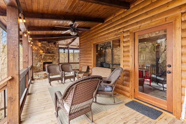 wooden deck featuring ceiling fan and an outdoor stone fireplace