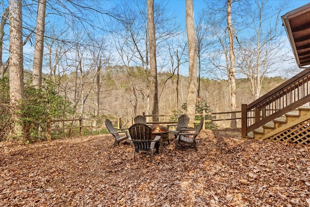 view of yard featuring stairway, a fire pit, and fence