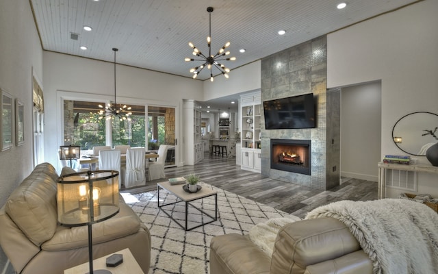 living room featuring wood ceiling, dark wood-type flooring, a fireplace, a high ceiling, and a notable chandelier