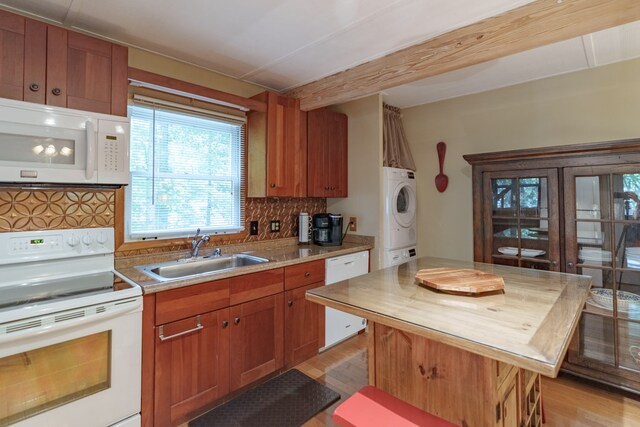 kitchen featuring light wood-type flooring, white appliances, stacked washer and dryer, sink, and a center island