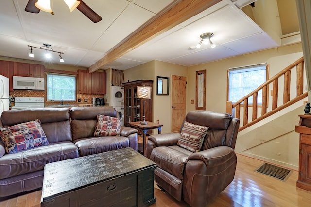 living room featuring ceiling fan, stacked washer and clothes dryer, sink, light hardwood / wood-style flooring, and track lighting