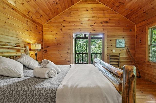 bedroom with access to exterior, wood walls, multiple windows, and hardwood / wood-style flooring