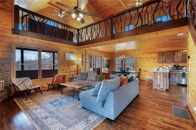 living room with hardwood / wood-style flooring, ceiling fan with notable chandelier, wooden ceiling, and wood walls