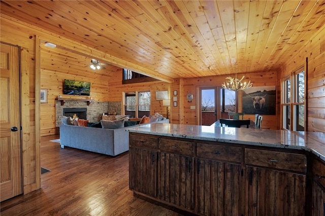 kitchen with wooden walls, a fireplace, dark wood-type flooring, wood ceiling, and dark brown cabinets