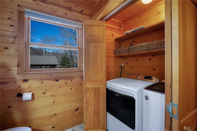 clothes washing area featuring wooden ceiling, separate washer and dryer, and wood walls