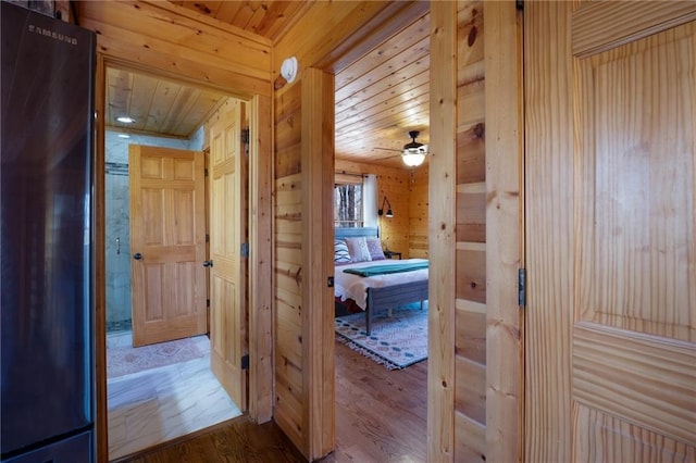 corridor featuring wood walls, wood-type flooring, and wooden ceiling