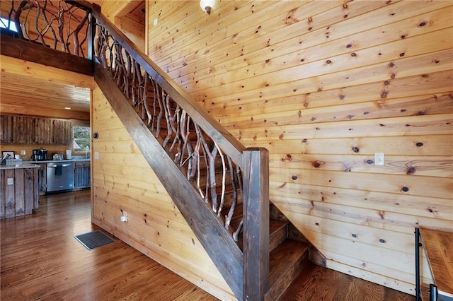 staircase featuring wood-type flooring and wooden walls