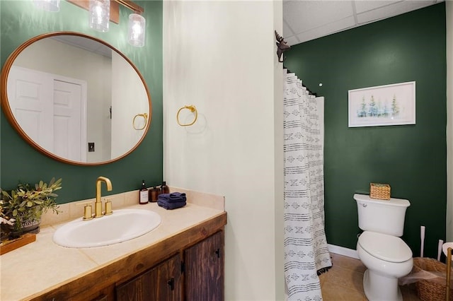 bathroom featuring a drop ceiling, vanity, tile patterned floors, and toilet