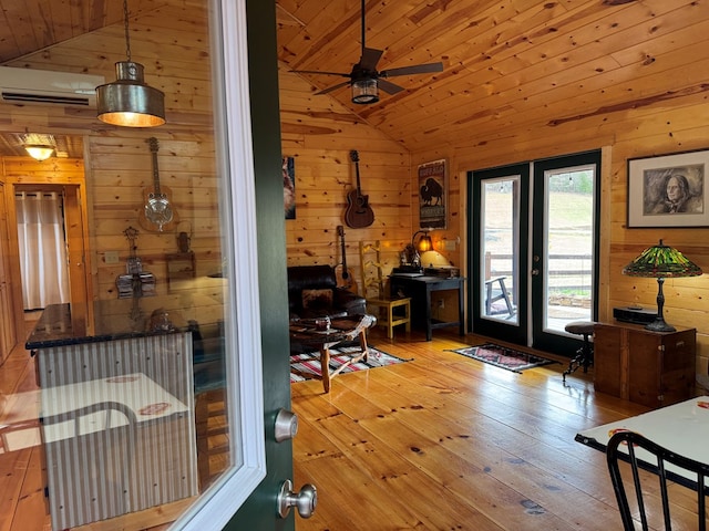 interior space featuring vaulted ceiling, light wood-type flooring, wood ceiling, and wooden walls