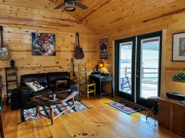 living room with french doors, vaulted ceiling, light hardwood / wood-style flooring, and wood walls