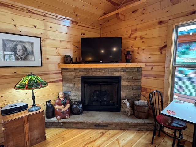 room details with hardwood / wood-style flooring, a stone fireplace, and wood walls