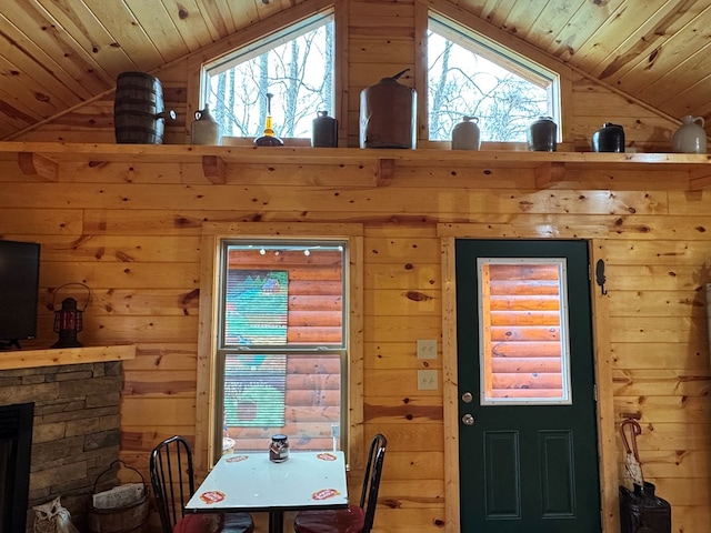 dining area featuring lofted ceiling, a healthy amount of sunlight, wood ceiling, and wood walls