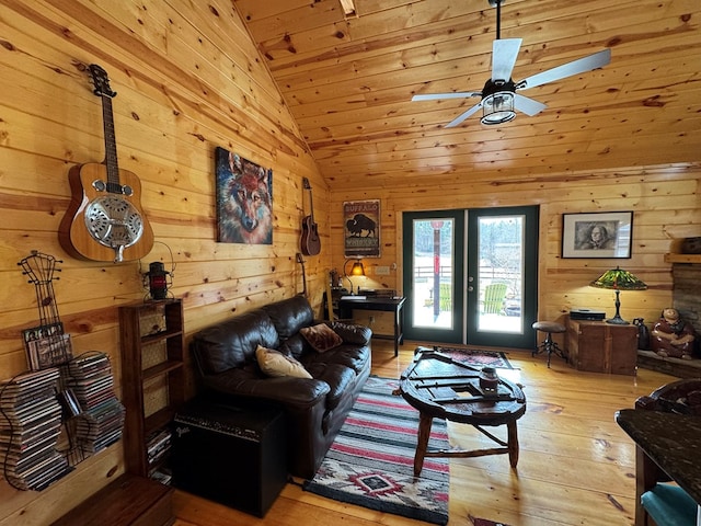 living room with light hardwood / wood-style flooring, high vaulted ceiling, french doors, and wood walls