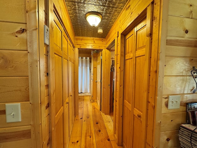 hallway with light hardwood / wood-style flooring and wood walls