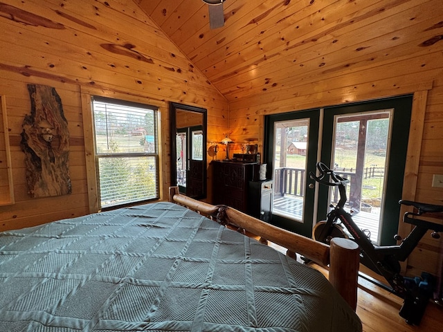 bedroom with lofted ceiling, wooden walls, multiple windows, and access to outside