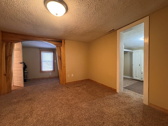 empty room with carpet, baseboards, and a textured ceiling