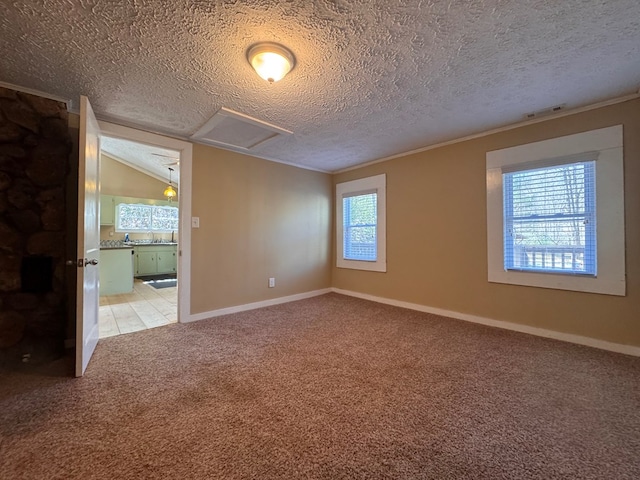 spare room with light carpet, attic access, visible vents, vaulted ceiling, and a textured ceiling