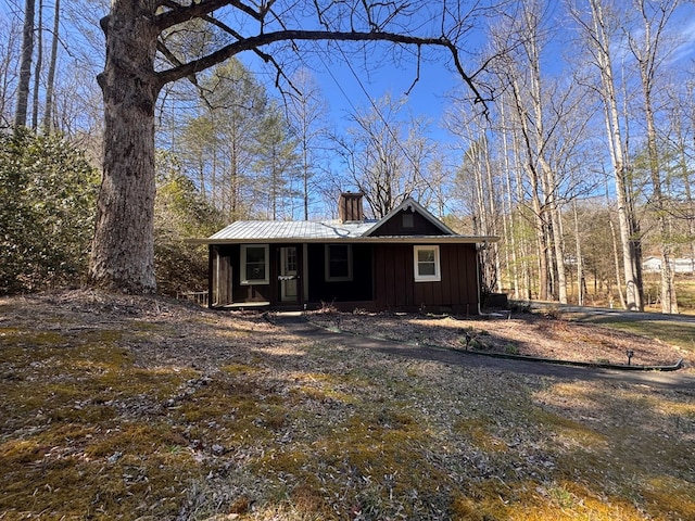 view of front of home with a chimney, metal roof, and board and batten siding