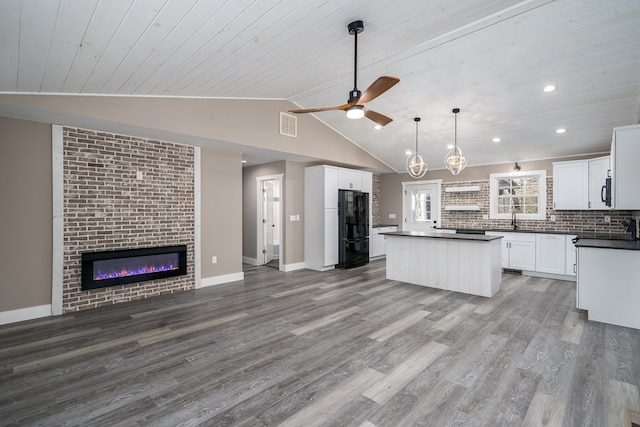 kitchen with white cabinetry, black fridge, hardwood / wood-style floors, pendant lighting, and a kitchen island