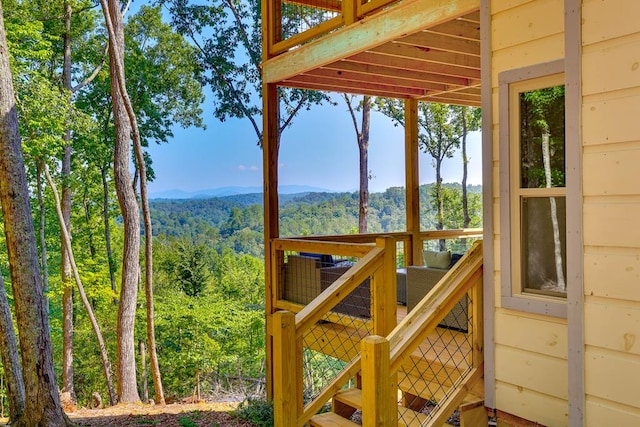 wooden terrace featuring a wooded view and a mountain view