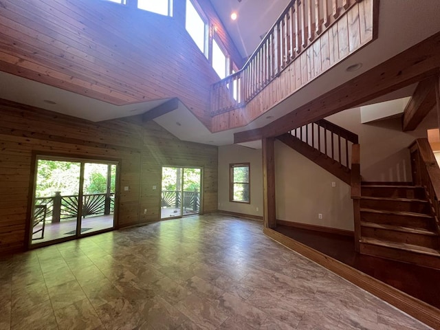 unfurnished living room with wood walls and a high ceiling