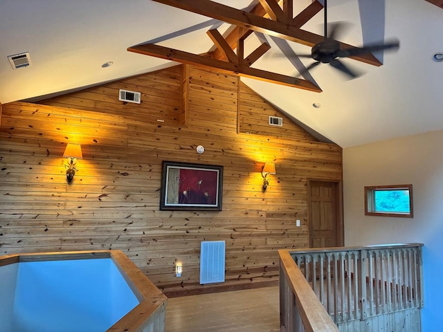 game room with hardwood / wood-style floors, ceiling fan, wood walls, and beam ceiling