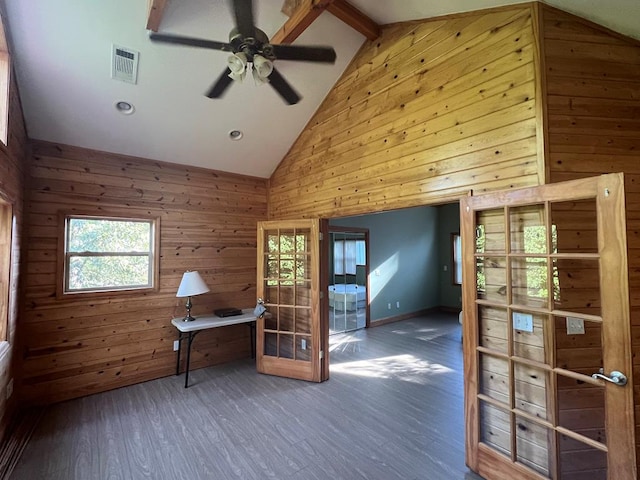 interior space featuring ceiling fan, dark hardwood / wood-style floors, lofted ceiling with beams, and wooden walls