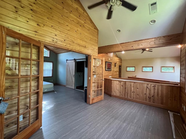 kitchen with wood walls, lofted ceiling with beams, dark hardwood / wood-style floors, a barn door, and ceiling fan