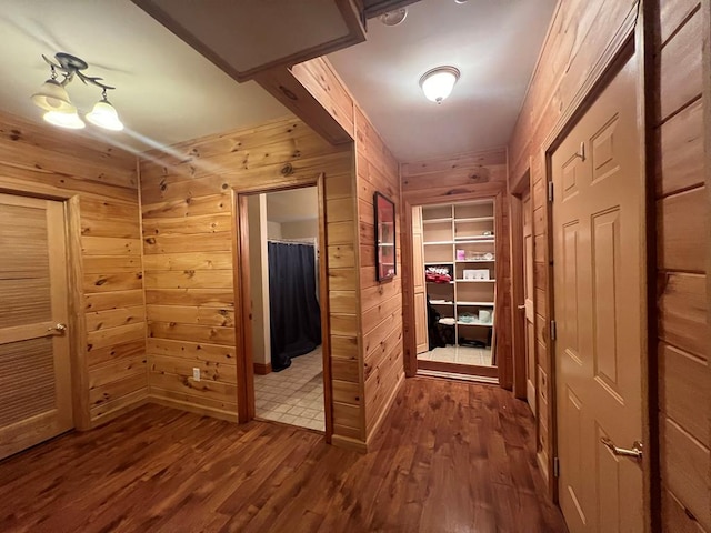 corridor with wood-type flooring, built in features, and wood walls