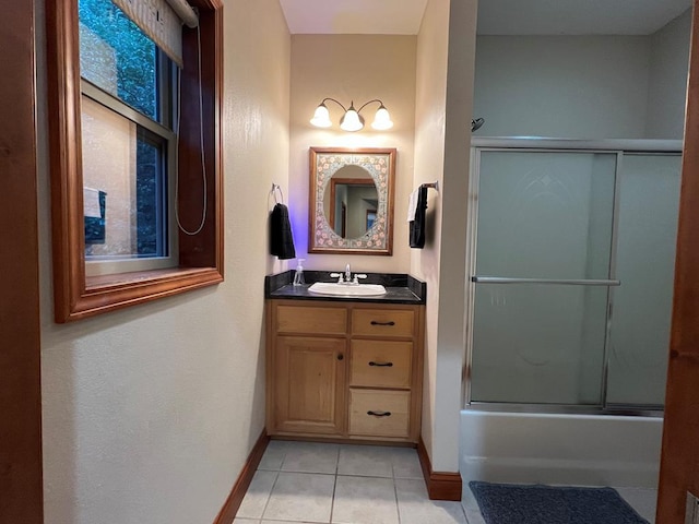 bathroom featuring tile patterned flooring, vanity, and enclosed tub / shower combo