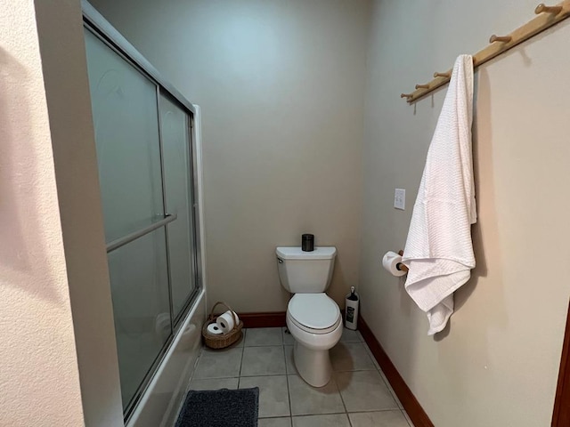 bathroom with tile patterned floors, bath / shower combo with glass door, and toilet