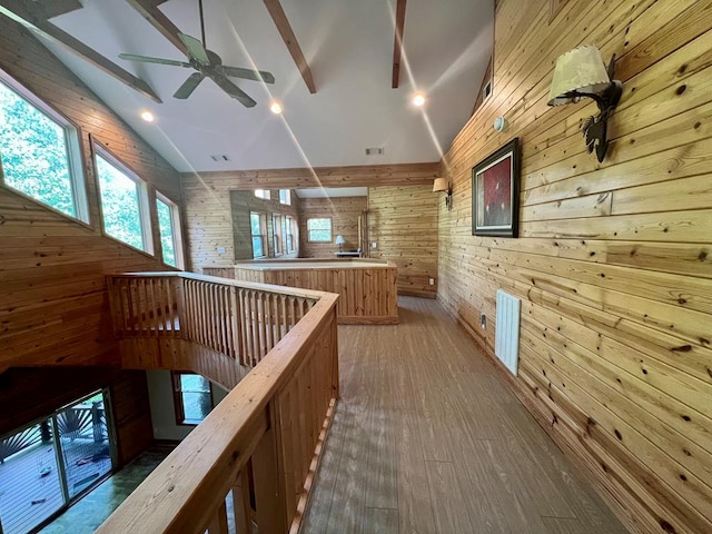 corridor featuring vaulted ceiling with beams, wooden walls, and hardwood / wood-style floors