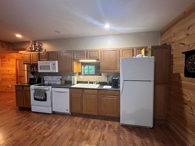 kitchen featuring wood walls, white appliances, backsplash, sink, and dark hardwood / wood-style floors