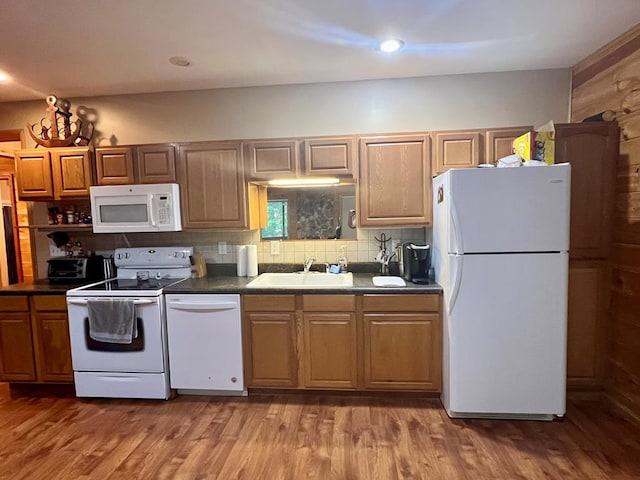 kitchen with backsplash, sink, hardwood / wood-style floors, and white appliances